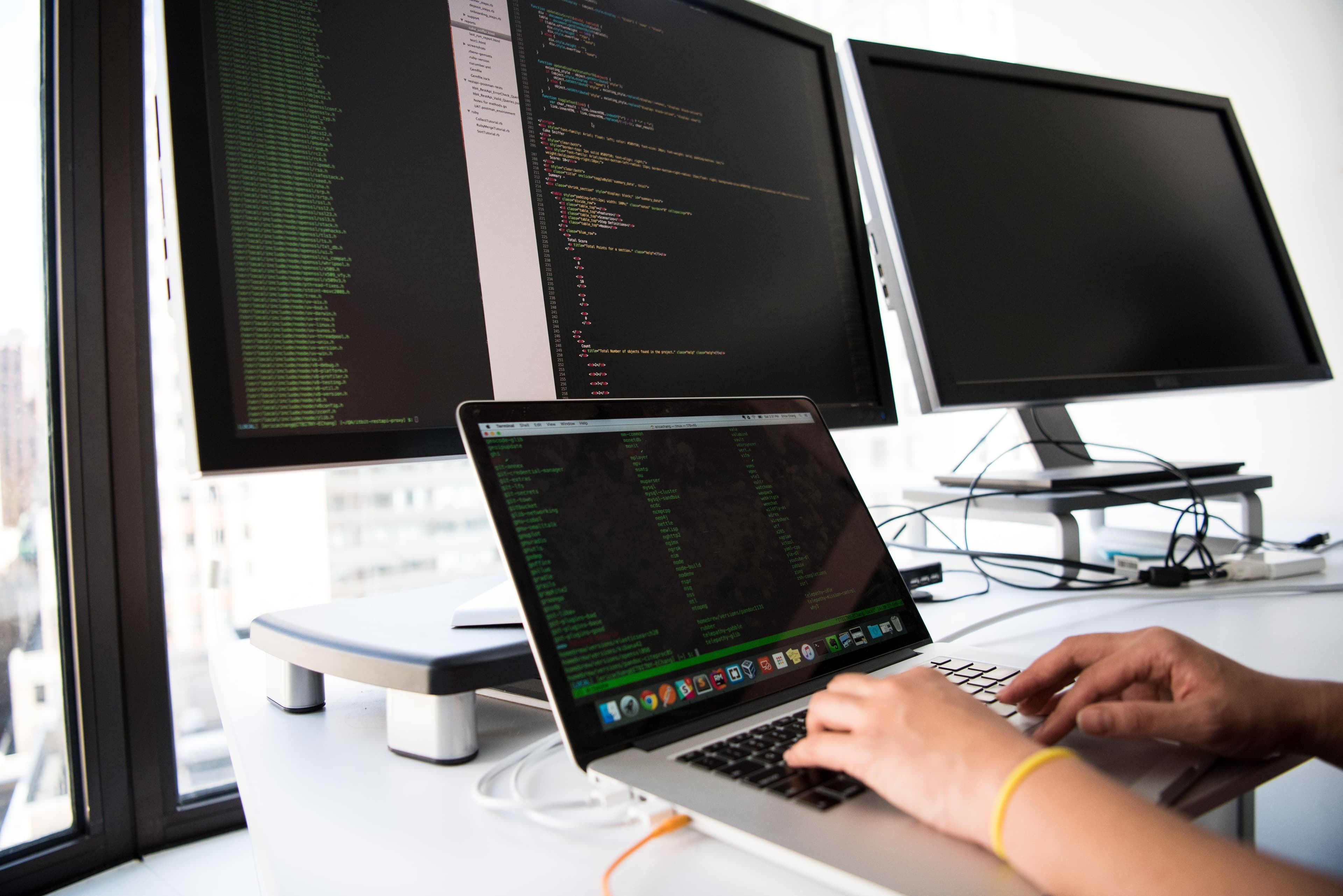 Programmer coding on multiple monitors software development